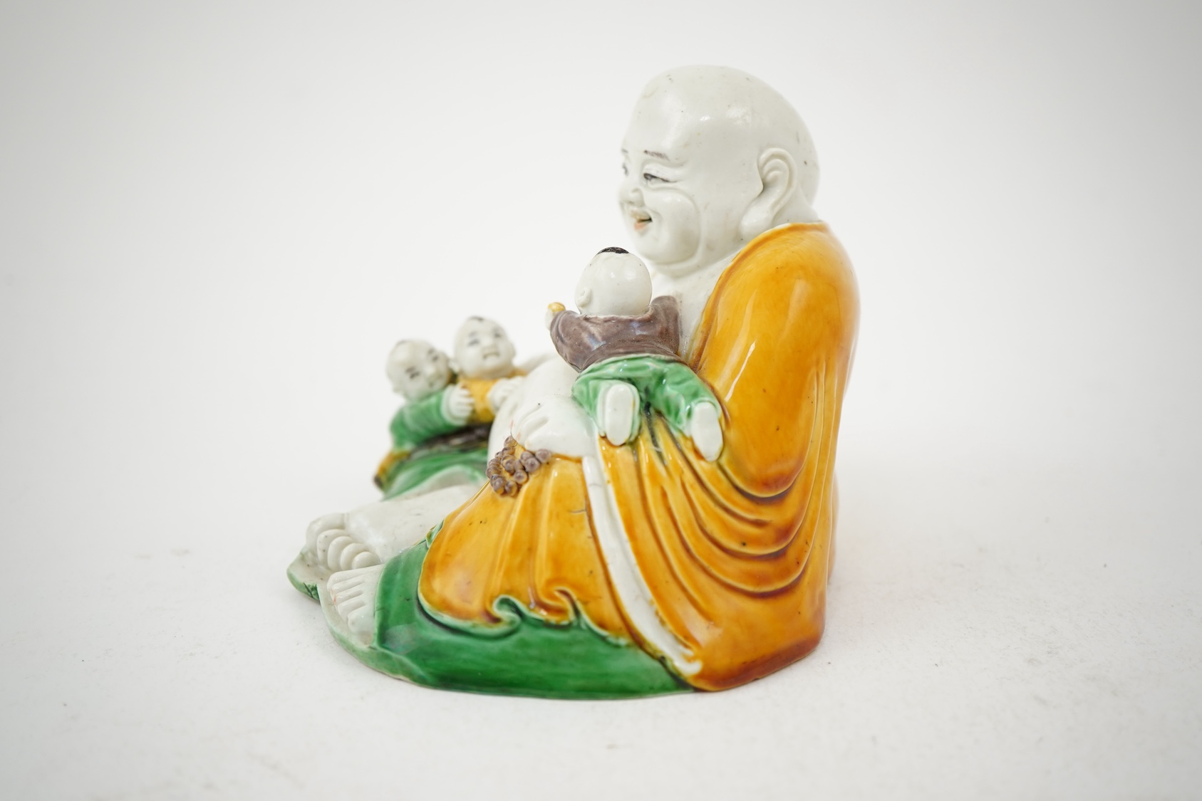 A Chinese sancai glazed biscuit group of Budai and three boys, 19th century